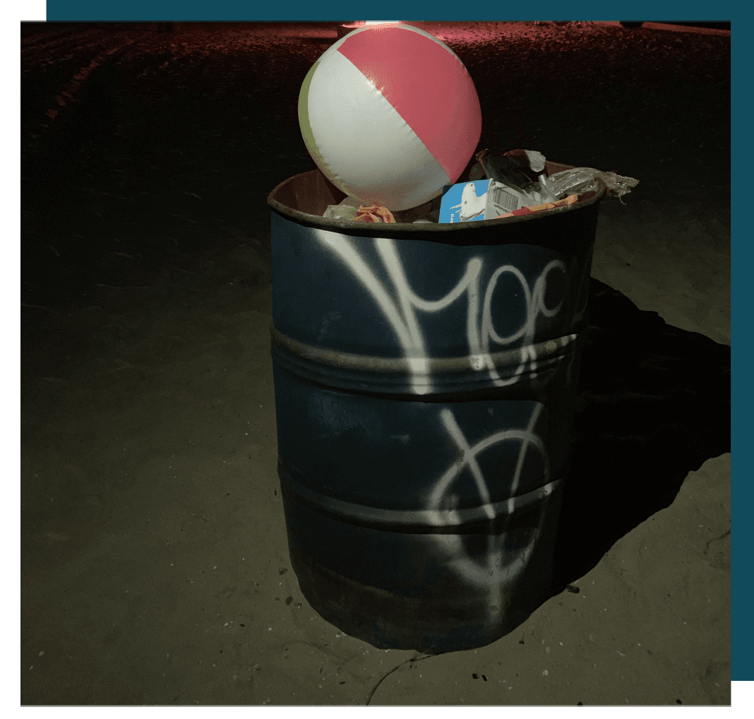 A trash can with graffiti on it and a ball in the top.